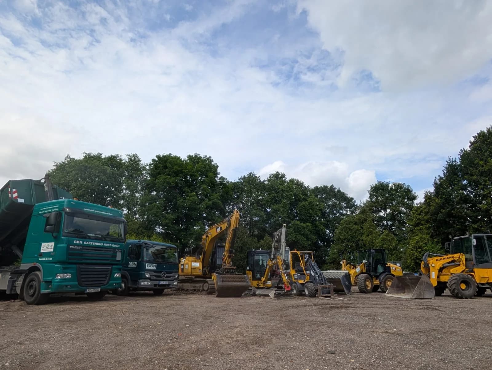 Umfangreicher Fuhrpark der GBN – Gartenbau Nord GmbH – grüne Lkw, Bagger und Radlader aufgereiht auf dem Betriebshof in Groß Nordende im Kreis Pinneberg