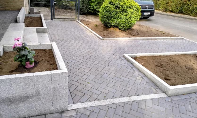 Gepflasterte Hofeinfahrt in Fischgrät mit Granit-Hochbeeten im Kreis Pinneberg