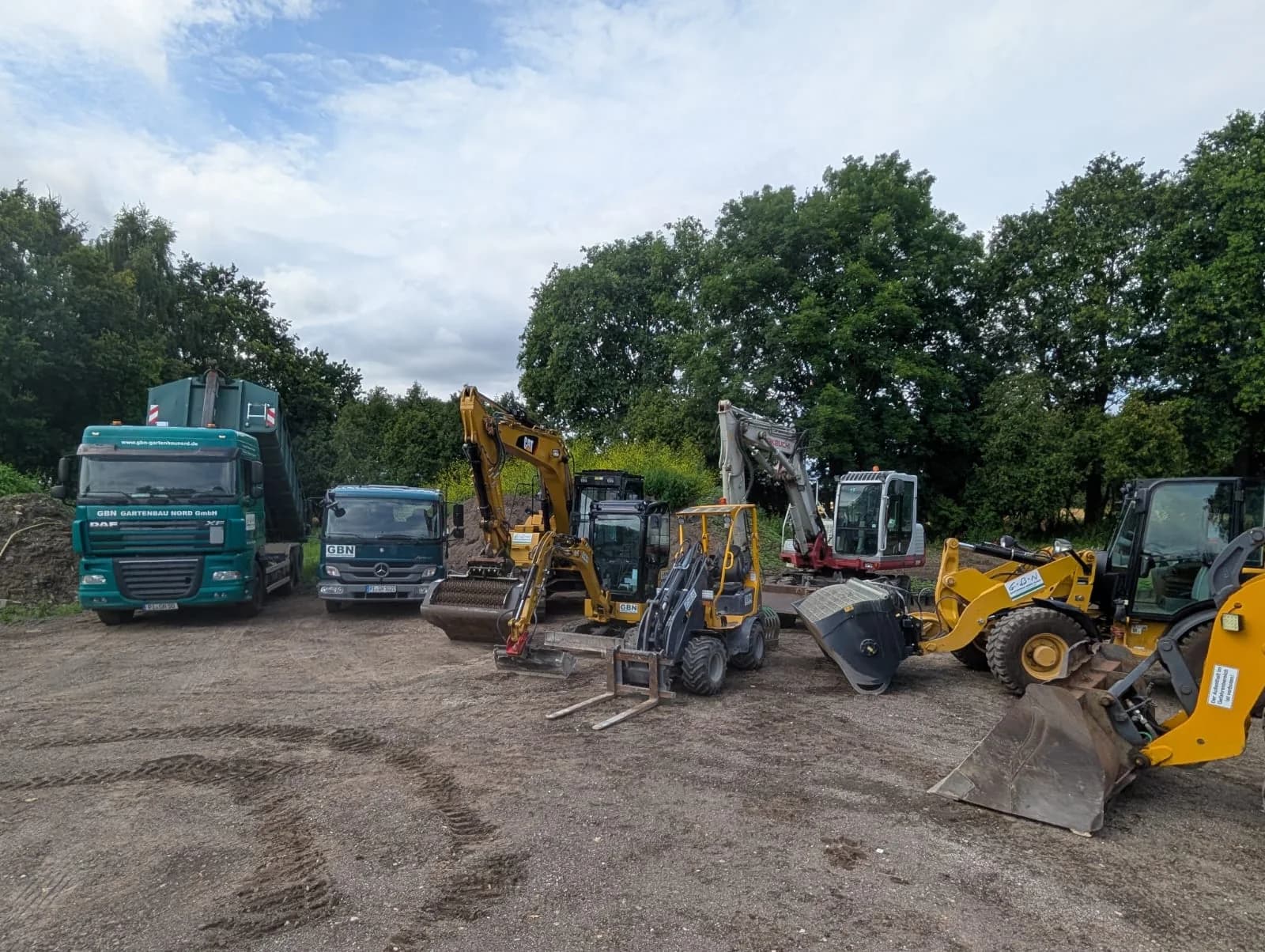 Aufgereihter Fuhrpark der GBN – Gartenbau Nord GmbH mit Lkw, Baggern und Radladern auf dem Hof in Groß Nordende, Kreis Pinneberg
